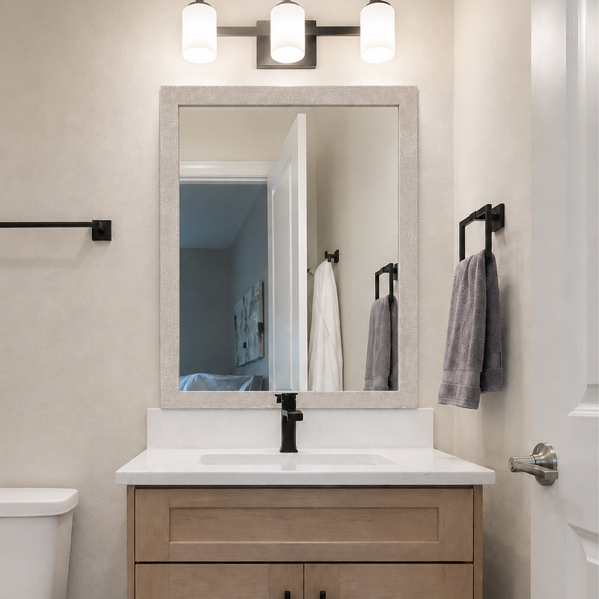 Highline Woven Silver Slim MirrorMate bathroom mirror frame above a light wood single vanity with black fixtures