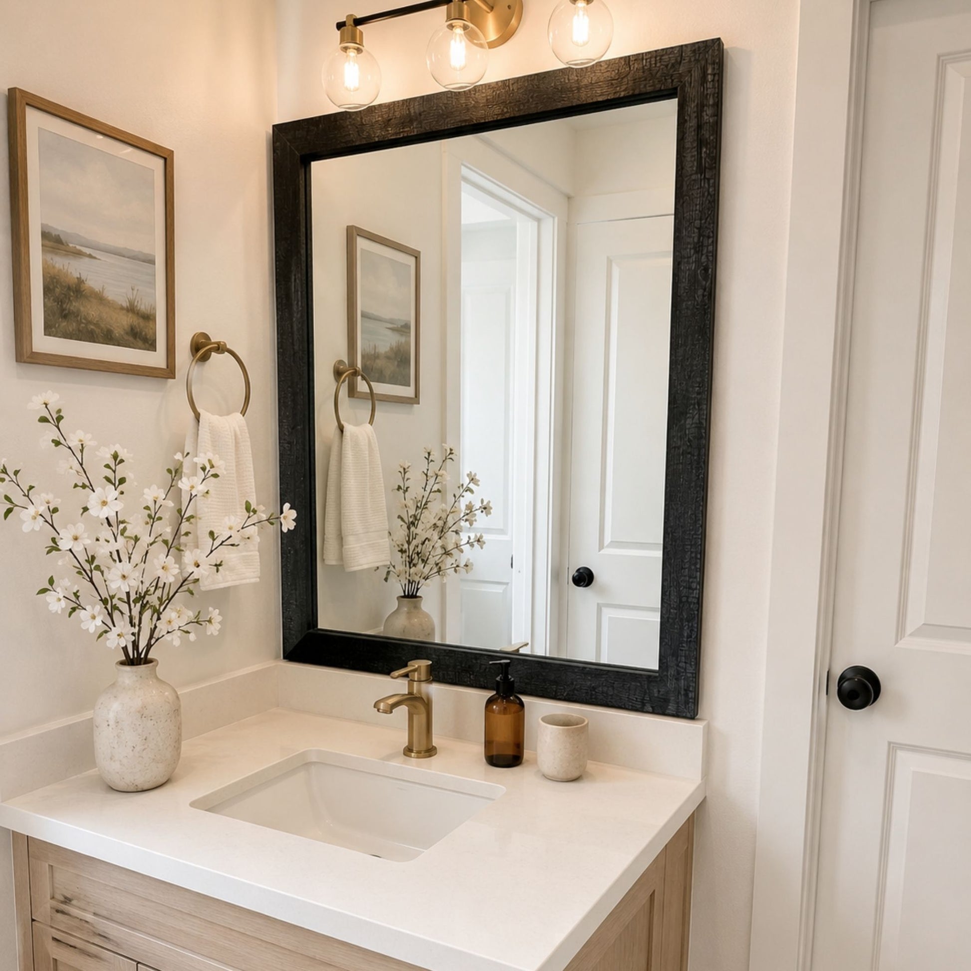 Big Sur Ash Black MirrorMate frame above a light wood vanity in a warm modern bathroom