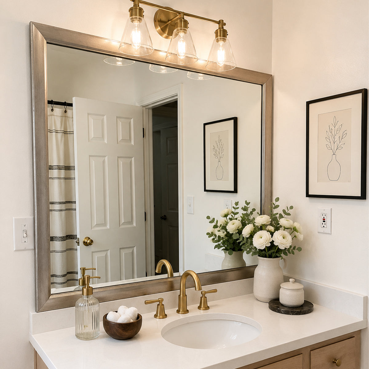 Pemaquid Old World Silver MirrorMate bathroom mirror frame above a light wood single vanity with a gold faucet