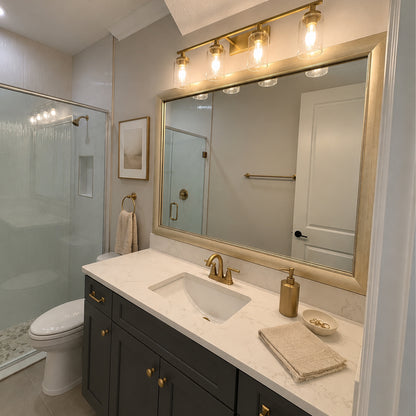 Solana Modern Gold MirrorMate bathroom mirror frame above a dark vanity in a modern bathroom