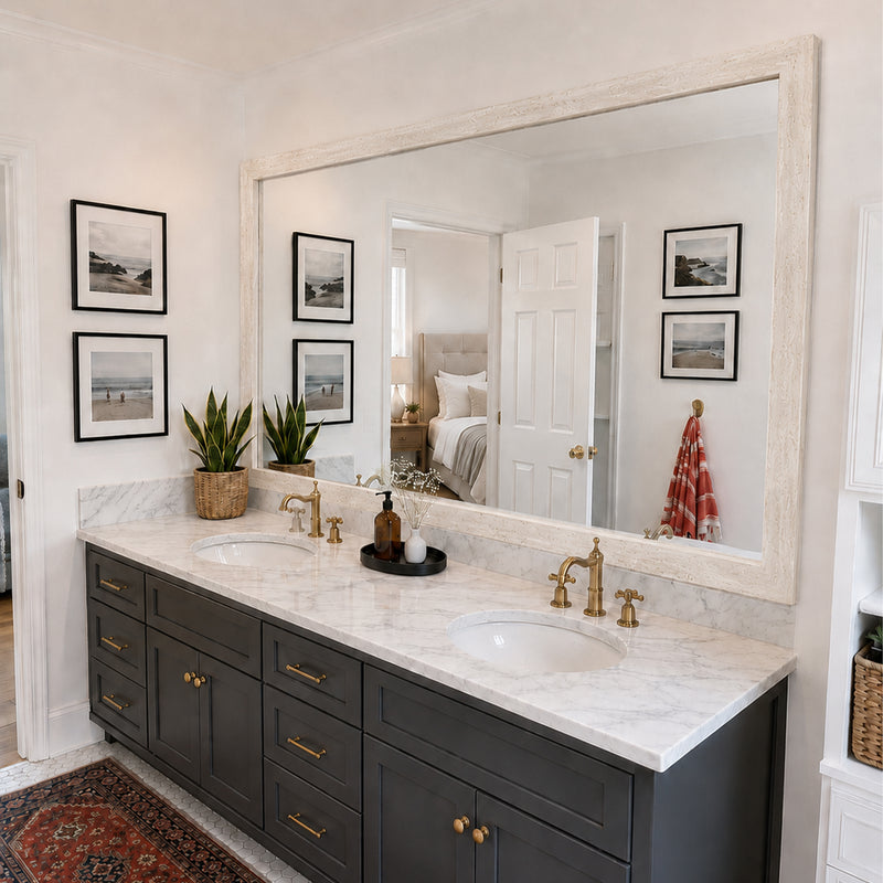 Tuscany Travertine MirrorMate bathroom mirror frame above a black double vanity with brass fixtures
